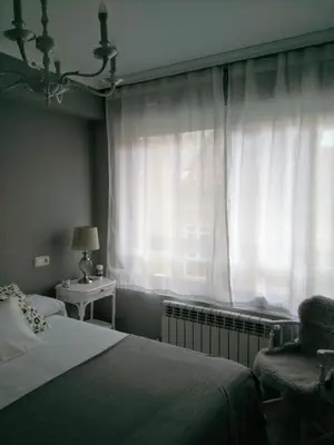a bedroom with a bed and a window with a chair at Torre Center in Santiago de Compostela