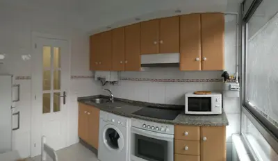 a kitchen with a washing machine and a microwave at Torre Center in Santiago de Compostela