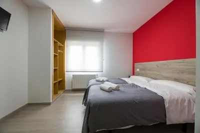 a bedroom with two beds and a red wall at A Chousa in Arzúa