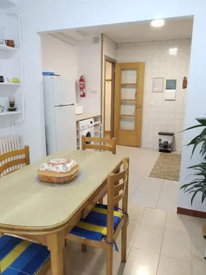 a kitchen with a wooden table and chairs and a kitchen with a refrigerator at Apartamento Casco Antiguo Ponferrada in Ponferrada