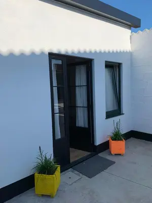 a white building with a black door and two plants at Casa Lourido in Sada