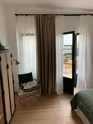 a bedroom with a chair and a bed and a balcony at Casa Lourido in Sada