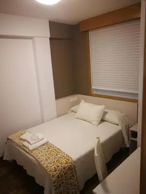 a small bedroom with a bed and a window at Pension Esquina in Melide