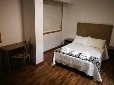 a bedroom with a bed and a chair and a desk at Pension Esquina in Melide