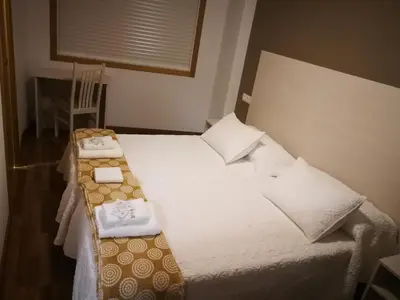 a bedroom with a bed with two towels on it at Pension Esquina in Melide