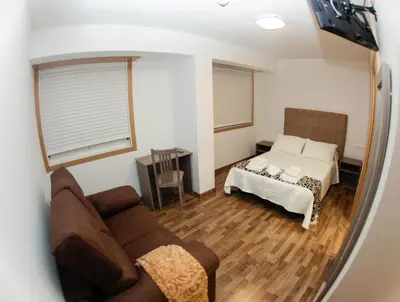 a living room with a couch and a bed at Pension Esquina in Melide