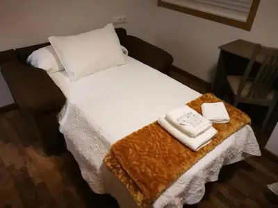 a bed with two towels on top of it at Pension Esquina in Melide