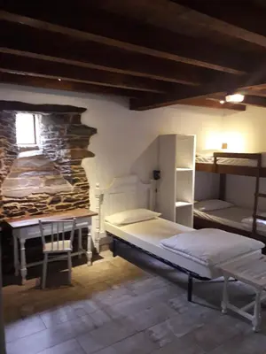 a bedroom with a bed and a desk and bunk beds at Albergue o Xistral in Abadín