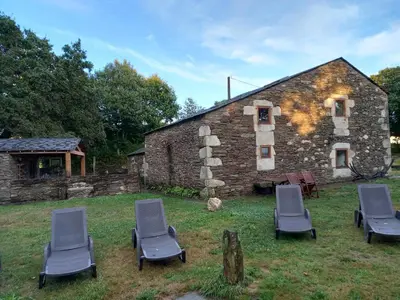 a group of chairs in front of a stone building at Albergue o Xistral in Abadín