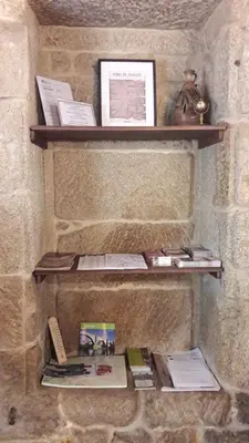 a stone wall with two wooden shelves with books at A Lareira De Allariz in Allariz