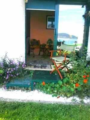 a porch with a chair and flowers in the grass at O ollo do Mar in Viveiro
