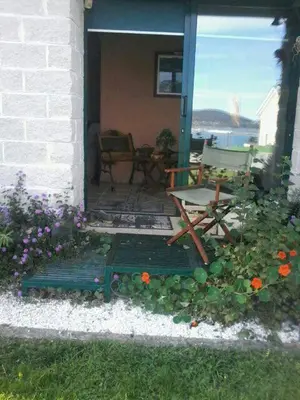 a porch with a chair and flowers in front of a house at O ollo do Mar in Viveiro