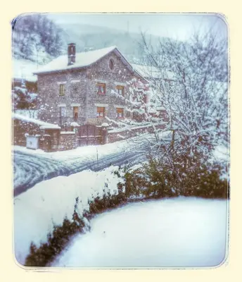 a house covered in snow in front of a yard at Casa Rural Calecha in Caboalles de Abajo