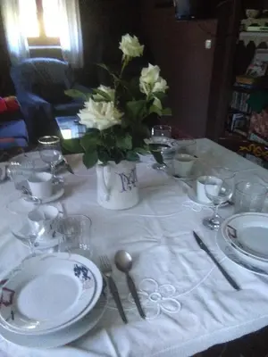 a table with white plates and a vase of flowers at Casa Rural Calecha in Caboalles de Abajo