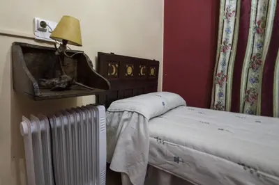 a bedroom with a bed with a radiator and a lamp at Casa Rural Calecha in Caboalles de Abajo