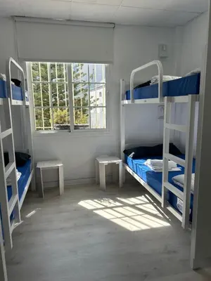 a room with two bunk beds and two windows at Albergue SCQ in Santiago de Compostela