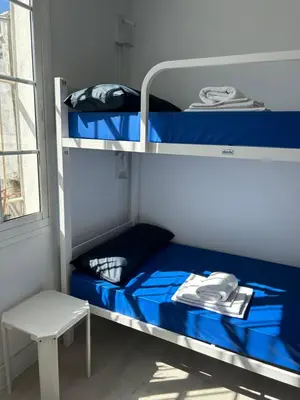 a bunk bed with blue sheets and a stool in a room at Albergue SCQ in Santiago de Compostela