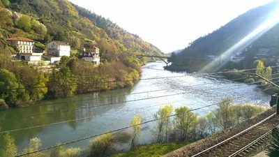 a river with a train on it next to a mountain at Casa Alpargateiro in Os Peares