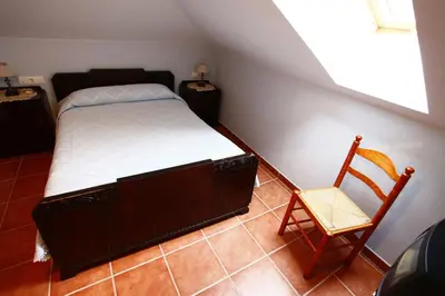 a small bedroom with a bed and a chair at Casa Alpargateiro in Os Peares