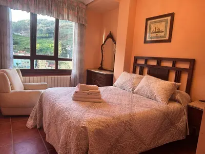 a bedroom with a bed and a chair and a mirror at Casa Alpargateiro in Os Peares