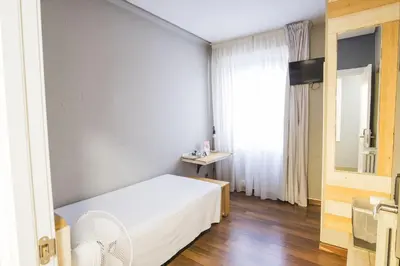 a bedroom with a white bed and a window at Hotel Alda Centro Ponferrada in Ponferrada