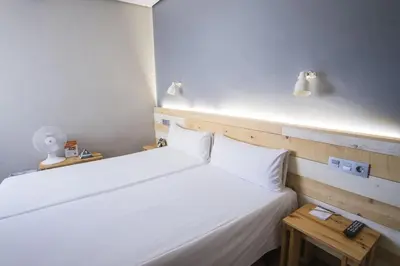 a bedroom with a white bed with a wooden headboard at Hotel Alda Centro Ponferrada in Ponferrada