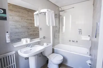 a bathroom with a toilet and a sink and a tub at Hotel Alda Centro Ponferrada in Ponferrada