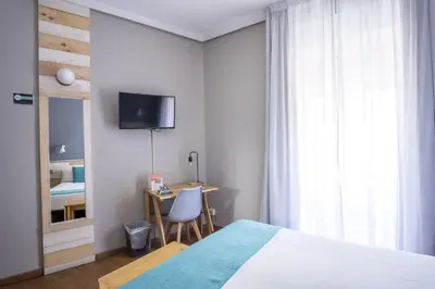 a bedroom with a bed and a desk and a tv at Hotel Alda Centro Ponferrada in Ponferrada