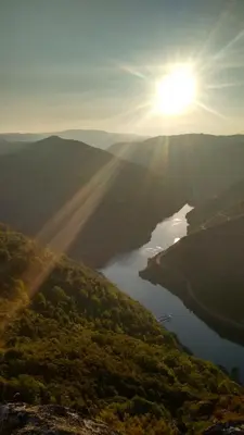 a view of a lake with the sun in the sky at casa do peso in Monforte de Lemos