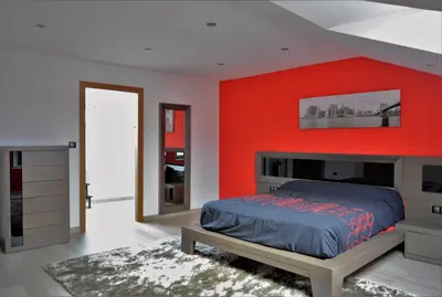 a bedroom with a bed and a red wall at Apartamento Vila O Valadouro in O Valadouro