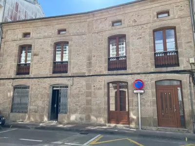 a stone building with brown doors and windows at Apartamento Vila O Valadouro in O Valadouro
