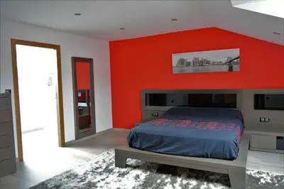 a bedroom with an orange wall with a bed and a mirror at Apartamento Vila O Valadouro in O Valadouro