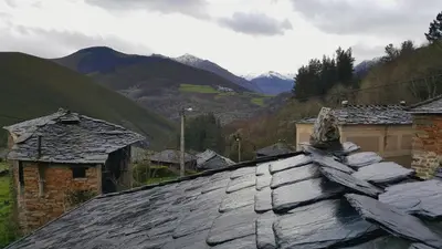 an old slate roof with mountains in the background at Apartamentos El Valledor in Tremado