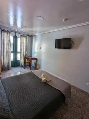 a bedroom with a bed and a television on the wall at H. O Lar in O Barco de Valdeorras