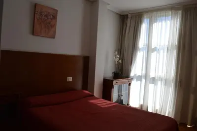 a bedroom with a red bed and a window at Hotel Os Caracoles in Pereiro de Aguiar