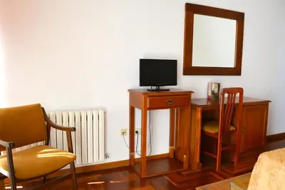 a room with a desk with a television and a mirror at Hotel Os Caracoles in Pereiro de Aguiar