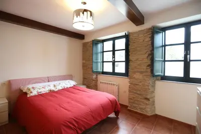 a bedroom with a red bed and some windows at Casa Pedrosa in Mondoñedo