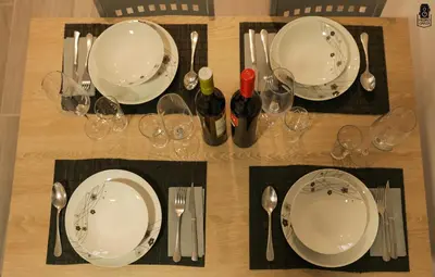a wooden table with plates and wine glasses on it at dpCristal City Apartments in Sarria