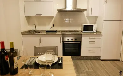 a kitchen with a table with glasses and wine bottles at dpCristal City Apartments in Sarria