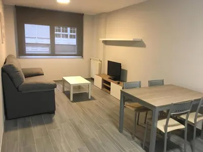 a living room with a table and a chair at dpCristal City Apartments in Sarria