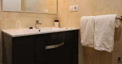 a bathroom with a white sink and a mirror at dpCristal City Apartments in Sarria