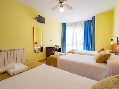 a hotel room with three beds and a window at Pensión Palas in Palas de Rei