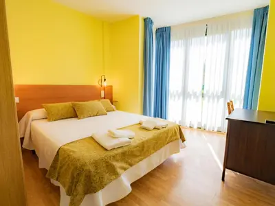 a yellow bedroom with a bed with towels on it at Pensión Palas in Palas de Rei