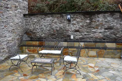 a group of chairs and a table in front of a stone wall at Isabel Artemis ES in San Tirso de Abres