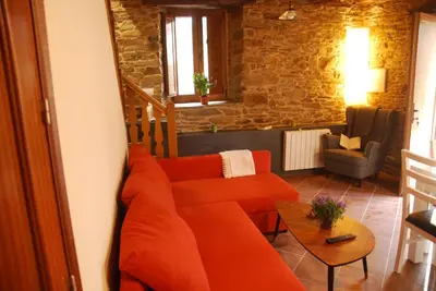 a living room with an orange couch and a chair at Isabel Artemis ES in San Tirso de Abres