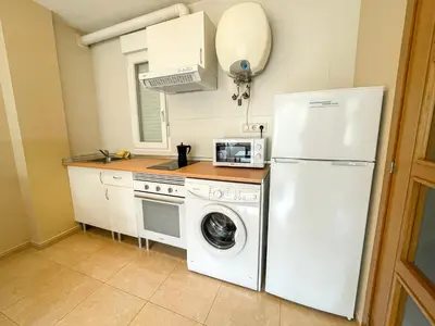 a kitchen with a white refrigerator and a washing machine at Alojamientos Playa de las Catedrales 3000 in Barreiros