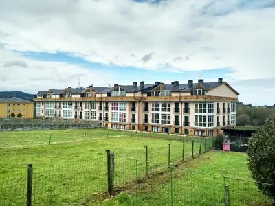 a large building with a field in front of it at Alojamientos Playa de las Catedrales 3000 in Barreiros
