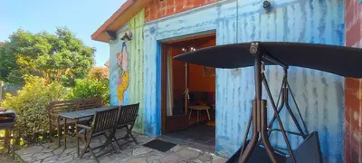 a blue building with a table and an umbrella at Apartamentos Rosa Jove in Cabañas