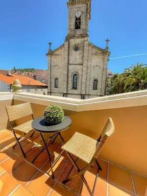 a table and chairs on a balcony with a clock tower at Apartamento La Iglesia in Caldas de Reis