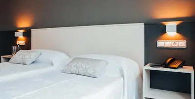 a bedroom with a bed with a phone and a television at Pensión Rúa Peregrino in Sarria